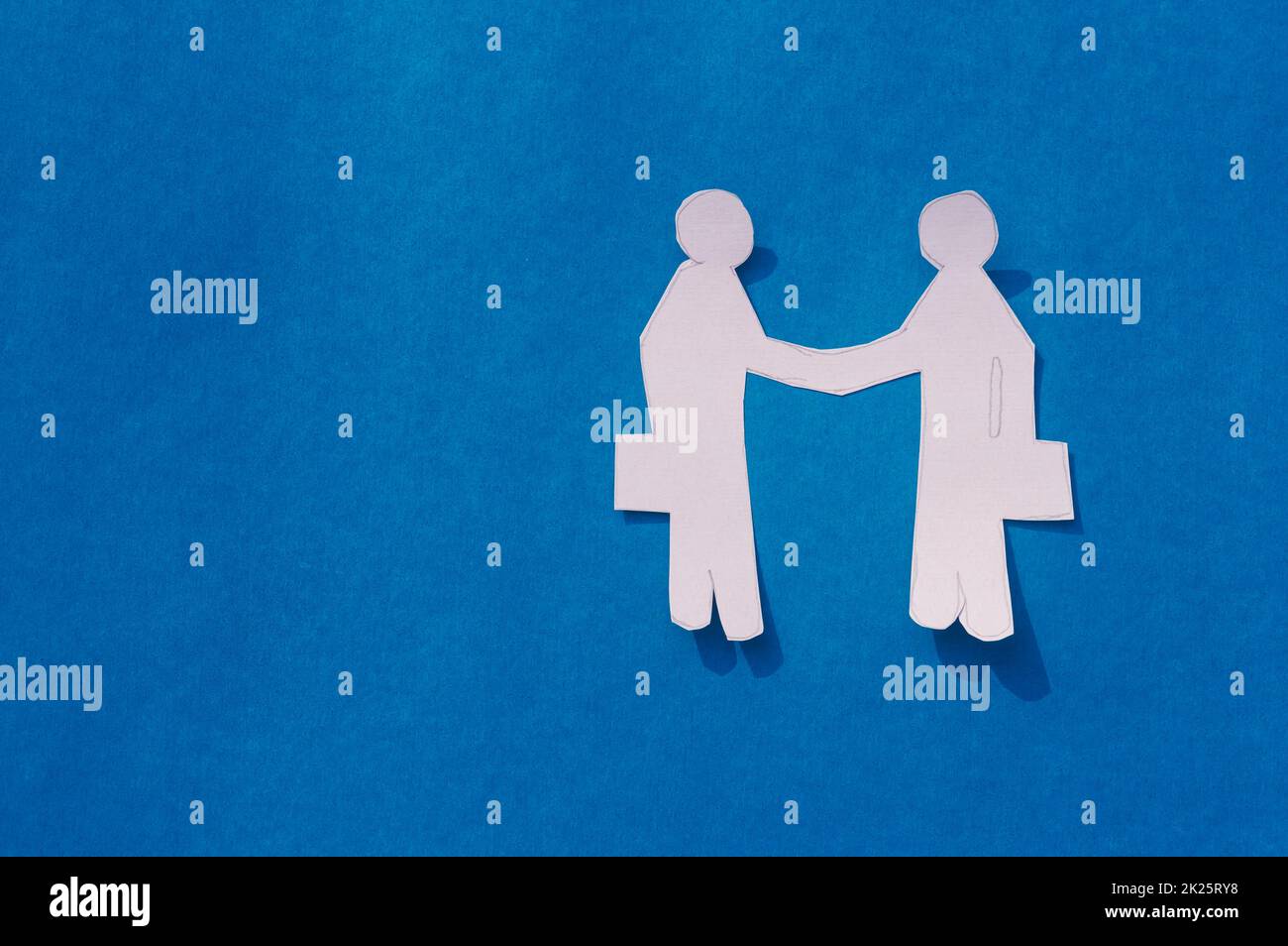 Zwei Geschäftsleute schütteln sich die Hand auf blauem Hintergrund. Origami Papercraft dekorative Formen und Figuren. Partnerschaft – Teamwork Business Deal Opportunity-Konzept. Bereich Kopieren. Stockfoto