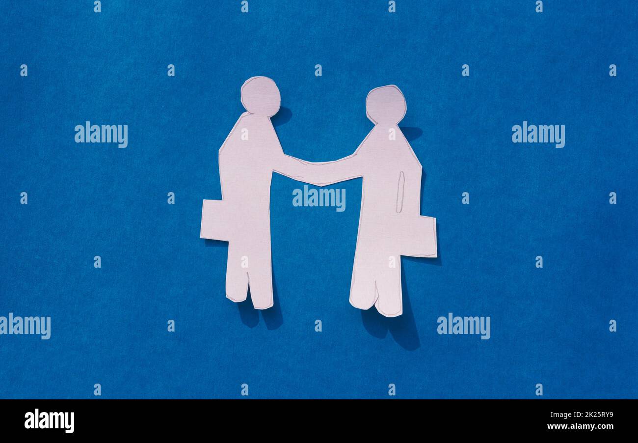 Zwei Geschäftsleute schütteln sich die Hand auf blauem Hintergrund. Origami Papercraft dekorative Formen und Figuren. Partnerschaft – Teamwork Business Deal Opportunity-Konzept. Bereich Kopieren. Stockfoto