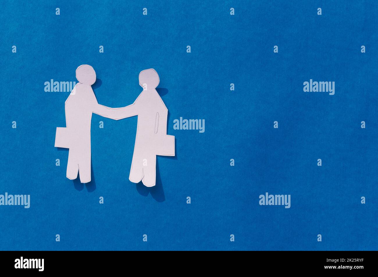 Zwei Geschäftsleute schütteln sich die Hand auf blauem Hintergrund. Origami Papercraft dekorative Formen und Figuren. Partnerschaft – Teamwork Business Deal Opportunity-Konzept. Bereich Kopieren. Stockfoto