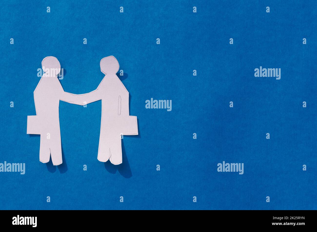 Zwei Geschäftsleute schütteln sich die Hand auf blauem Hintergrund. Origami Papercraft dekorative Formen und Figuren. Partnerschaft – Teamwork Business Deal Opportunity-Konzept. Bereich Kopieren. Stockfoto