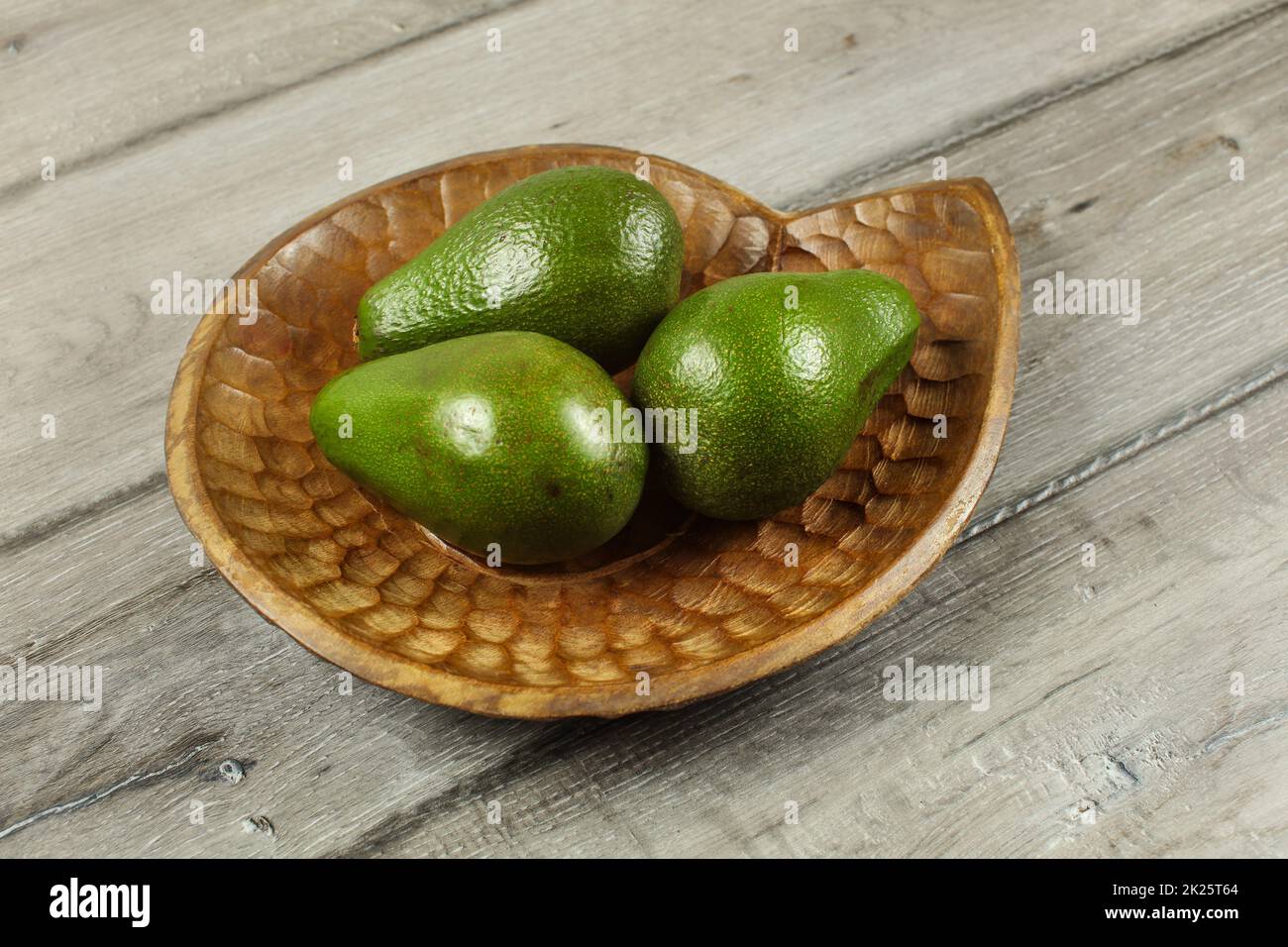 Ganze drei grüne Avocados auf Holz geschnitzte Schüssel. Stockfoto