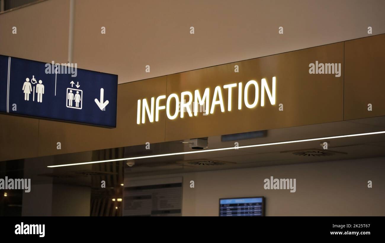 'Informationen' neon Label über infopoint Schreibtisch, und hängend Toiletten und Aufzüge Piktogramm am Flughafen in Halle. Stockfoto