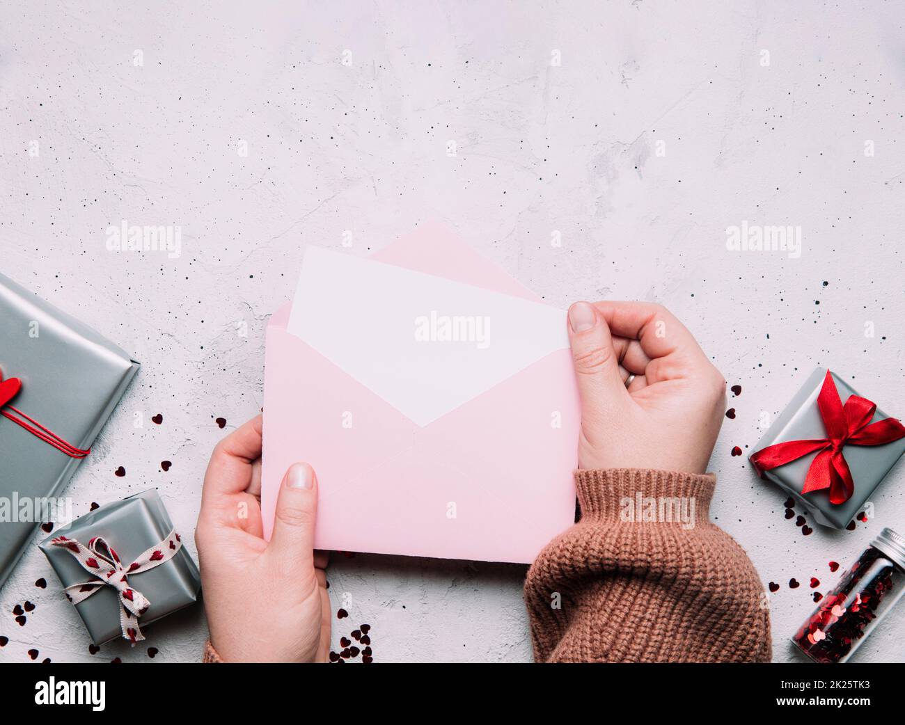 Weibliche Hände halten Liebesbriefe in Umschlag, Valentinstagskarte Stockfoto