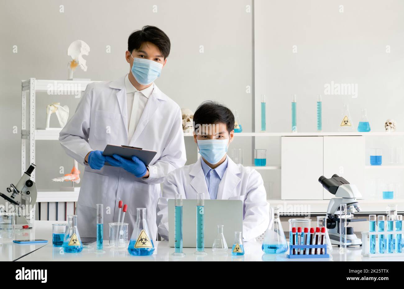 Zwei Wissenschaftler mit Gesichtsmaske und Kittel arbeiten im Labor. Omicron Strain Testing Process, Coronavirus Disease 2019. Stockfoto