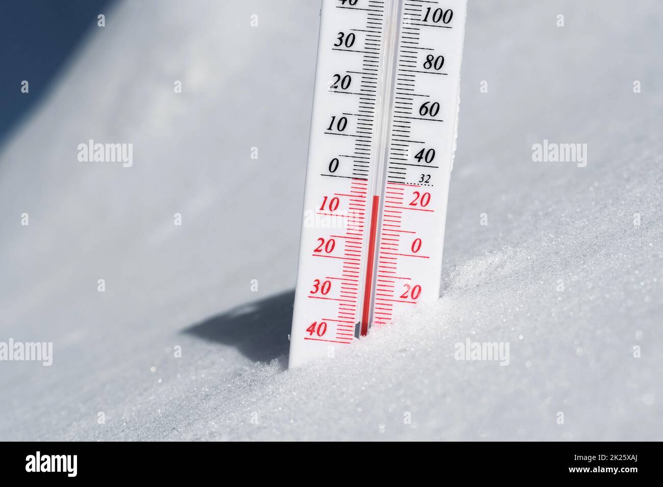 Das Thermometer liegt auf dem Schnee und zeigt eine negative Temperatur bei kaltem Wetter am blauen Himmel an.Meteorologische Bedingungen mit niedrigen Luft- und Umgebungstemperaturen.Klimawandel und globale Erwärmung Stockfoto