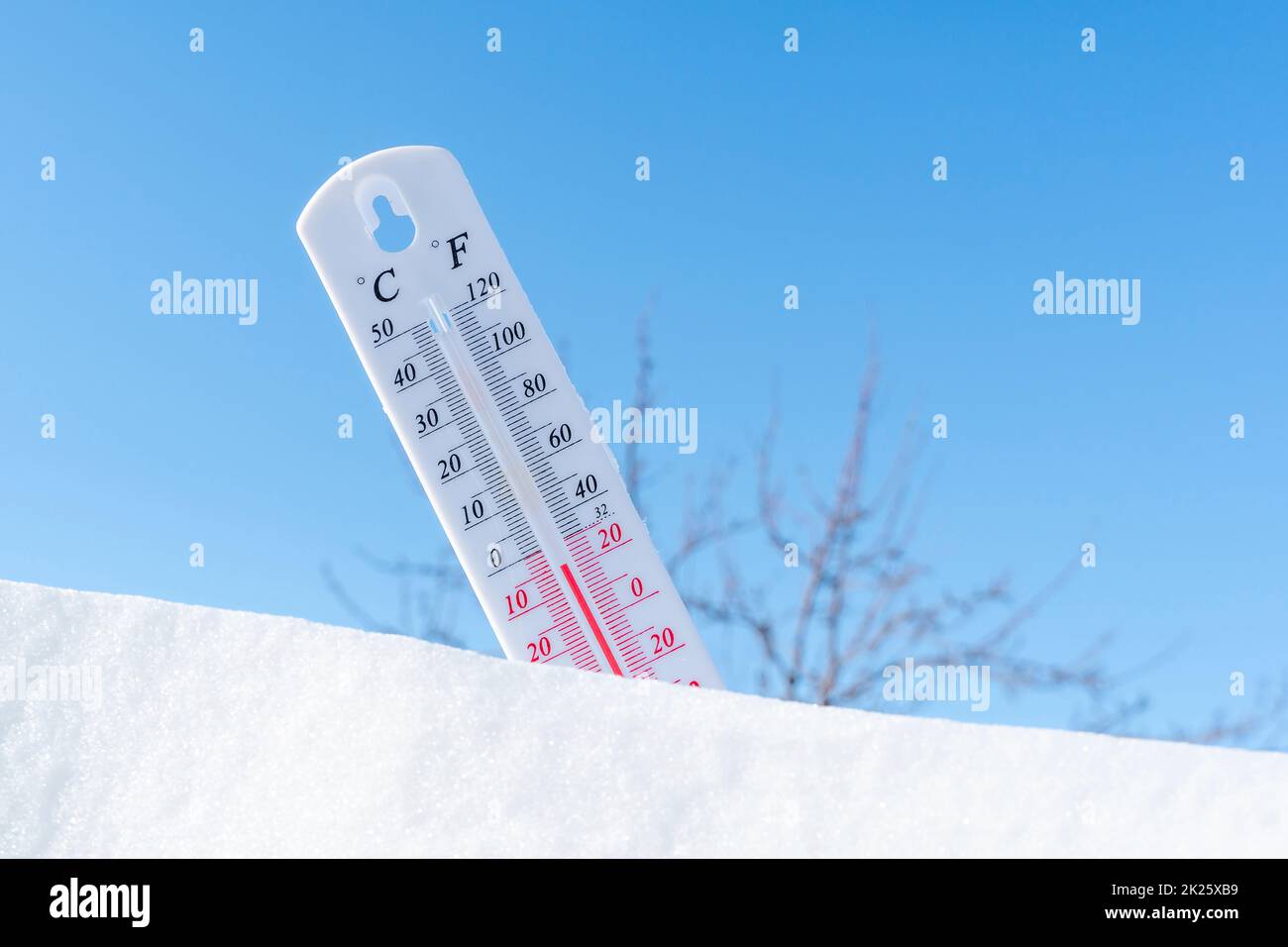 Das Thermometer liegt im Winter auf dem Schnee und zeigt eine niedrige ...