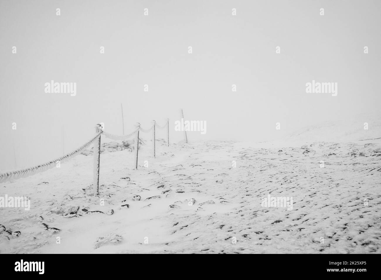 Kettenzäune bedeckt mit Eis und Schnee auf einem gefährlichen Abschnitt des Weges in den Bergen. Stockfoto