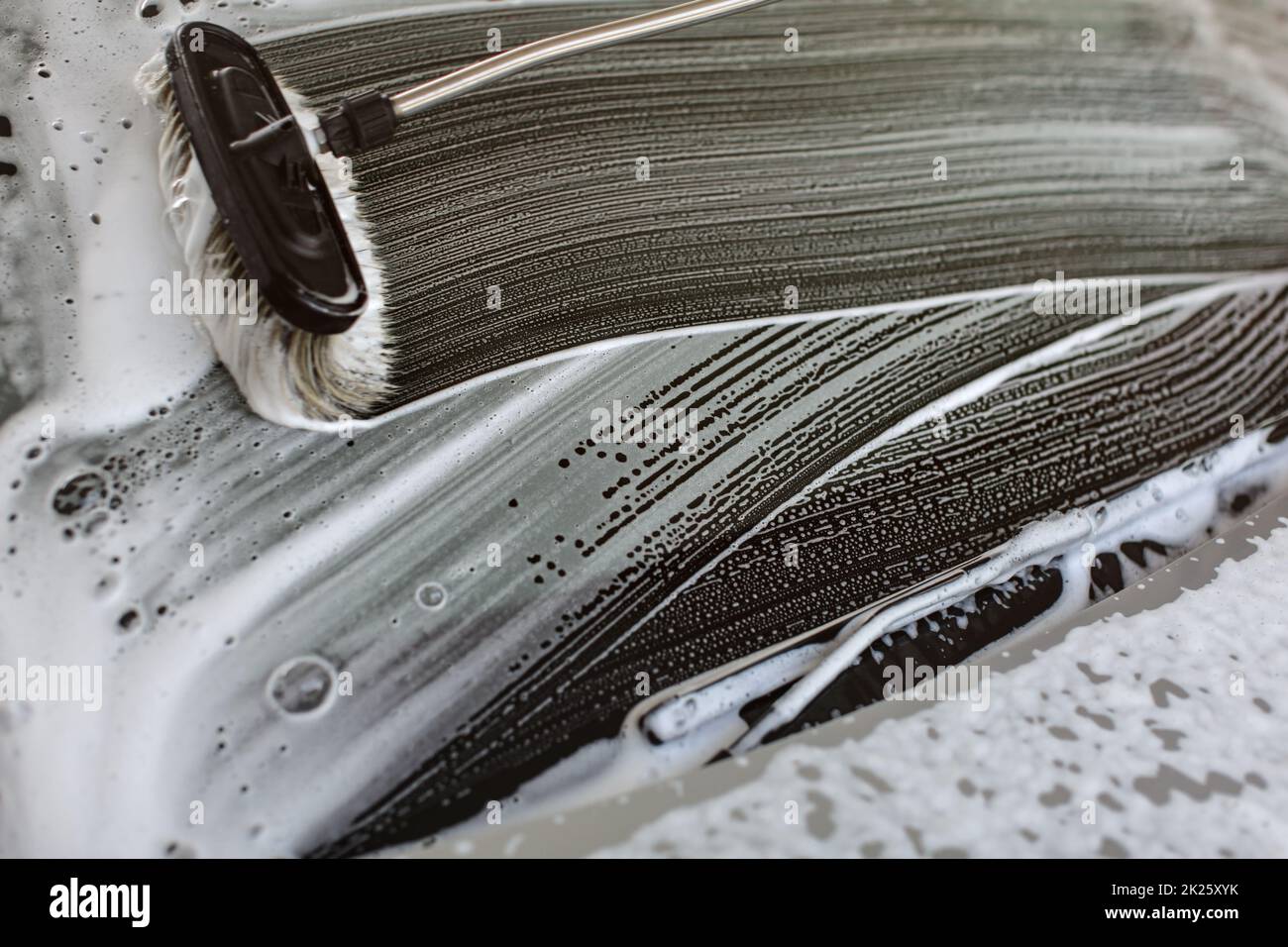 Bürste aus Anschläge in weißer Schaum auf der Windschutzscheibe eines Autos in der Waschstraße gewaschen Stockfoto