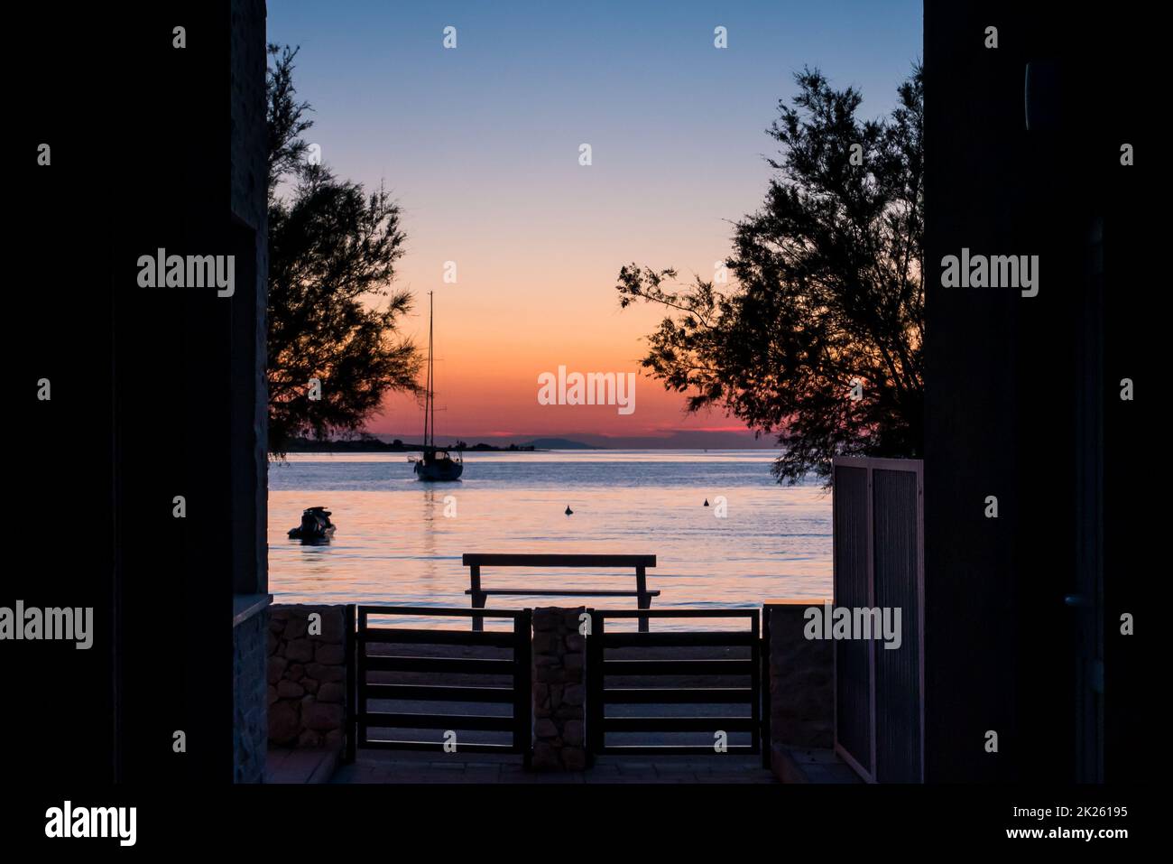 Blick vom Hof auf das Meer, Segelboot und ein wunderschöner Sonnenuntergang Stockfoto