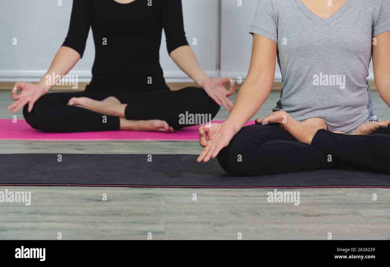 Yoga-meditierende Frauen in Lotusposition mit Mudra während des Yoga-Kurses. Ich trainiere mit schwarzem Hemd und weißer Hose. Gesundheitskonzept.. Stockfoto