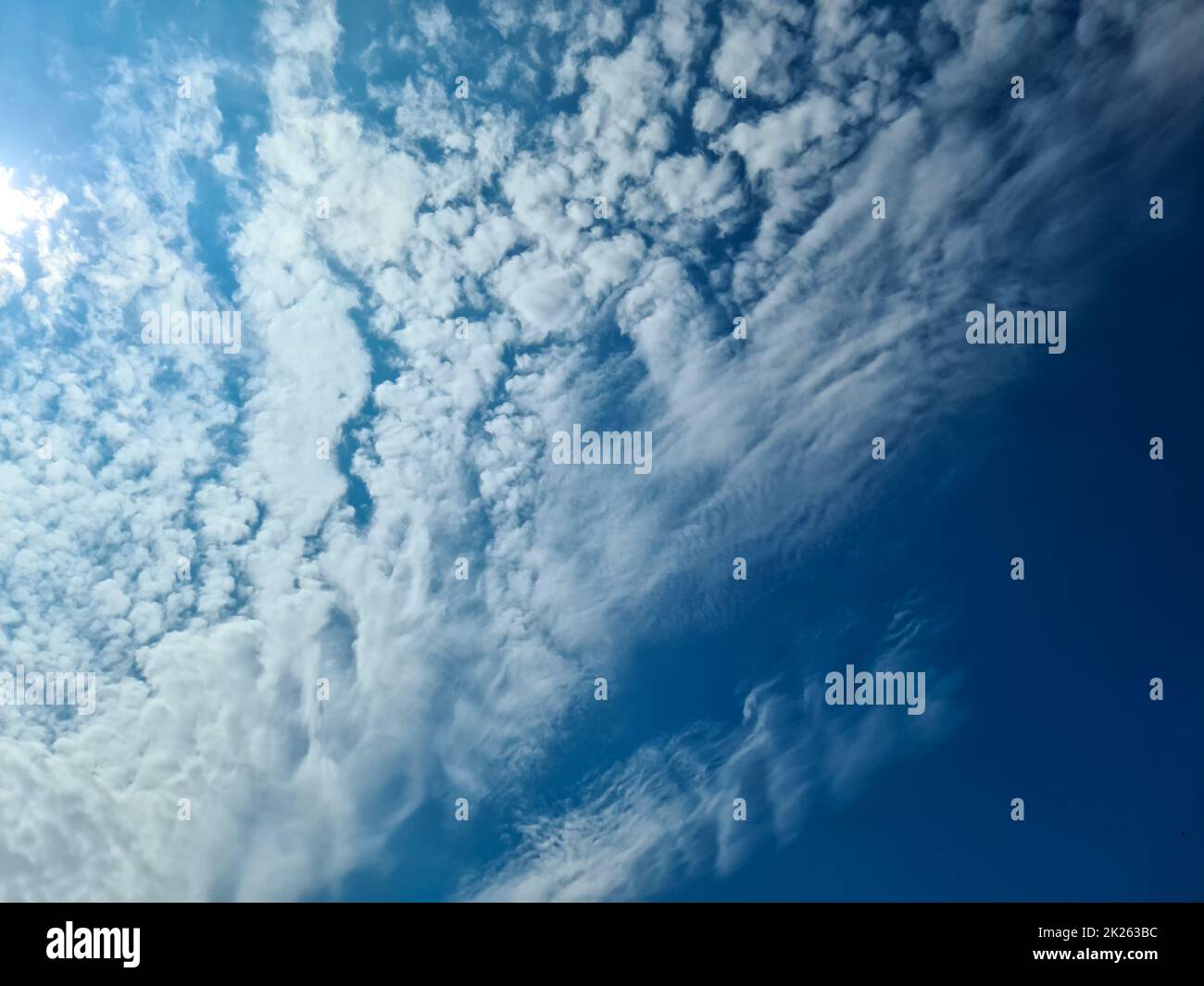 Wunderschöner Blick auf die Sonnenstrahlen mit einigen Lichtreflexionen und Wolken in einem blauen Himmel Stockfoto