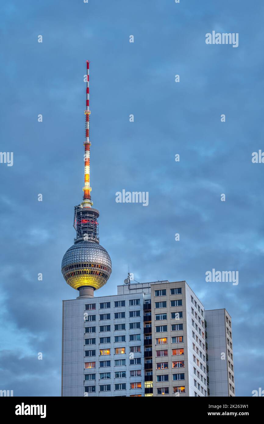 Der berühmte Fernsehturm von Berlin in der Abenddämmerung mit einem typischen DDR-Fertighaus Stockfoto