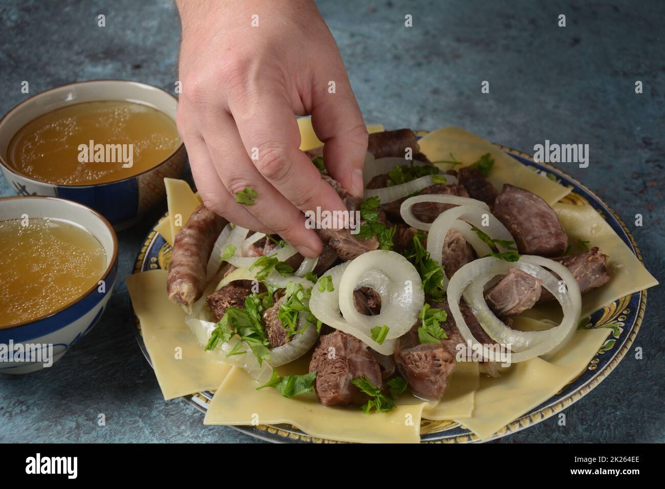 Beshbarmak – Kasachisches Nationalgericht, zubereitet mit Fleisch und Nudeln. Nahaufnahme des Schüssels Beshbarmak auf einem Teller auf dem Tisch. Große Stücke gedünstetes Fleisch und Zwiebeln Stockfoto