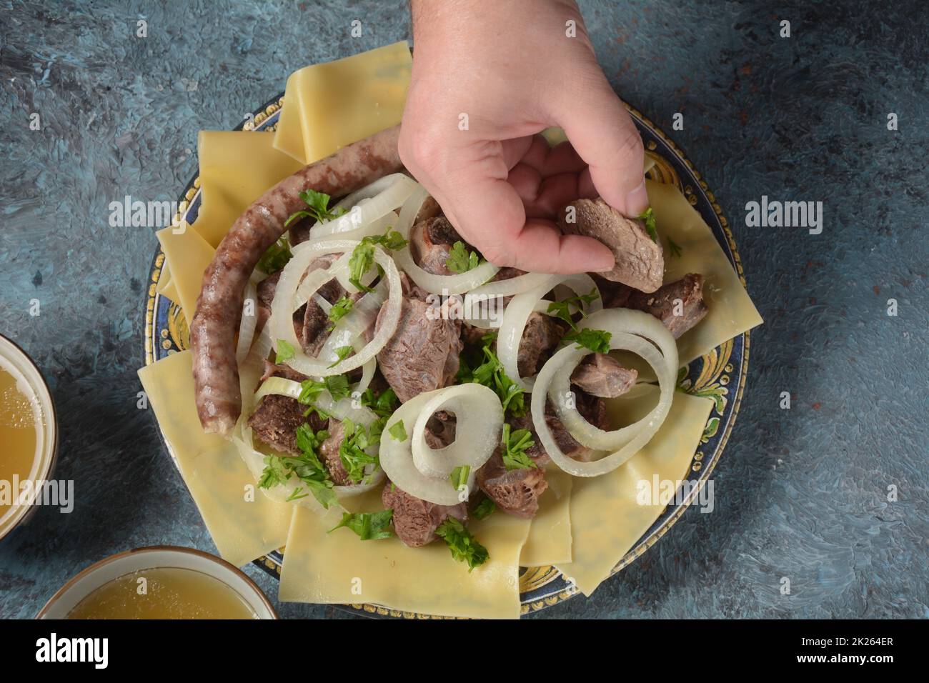Beshbarmak – Kasachisches Nationalgericht, zubereitet mit Fleisch und Nudeln. Nahaufnahme des Schüssels Beshbarmak auf einem Teller auf dem Tisch. Große Stücke gedünstetes Fleisch und Zwiebeln Stockfoto