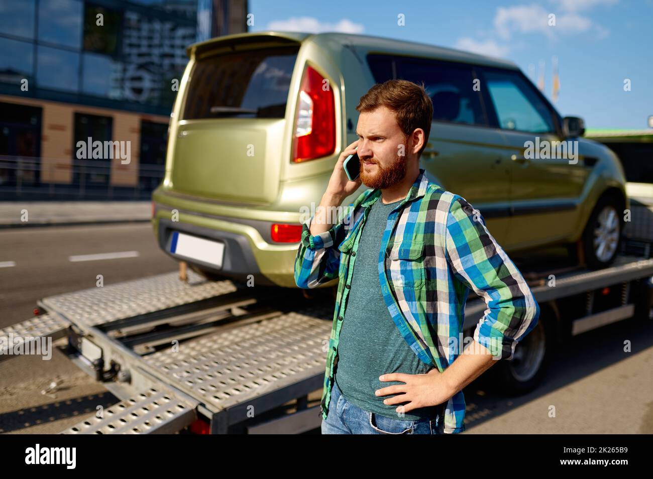 Mann ruft an, während der Abschleppwagen das Auto abholt Stockfoto
