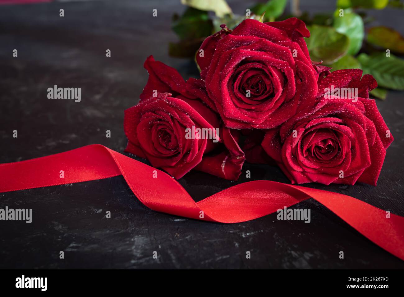 Rote Rosen mit Band auf grauer Steinplatte Stockfoto