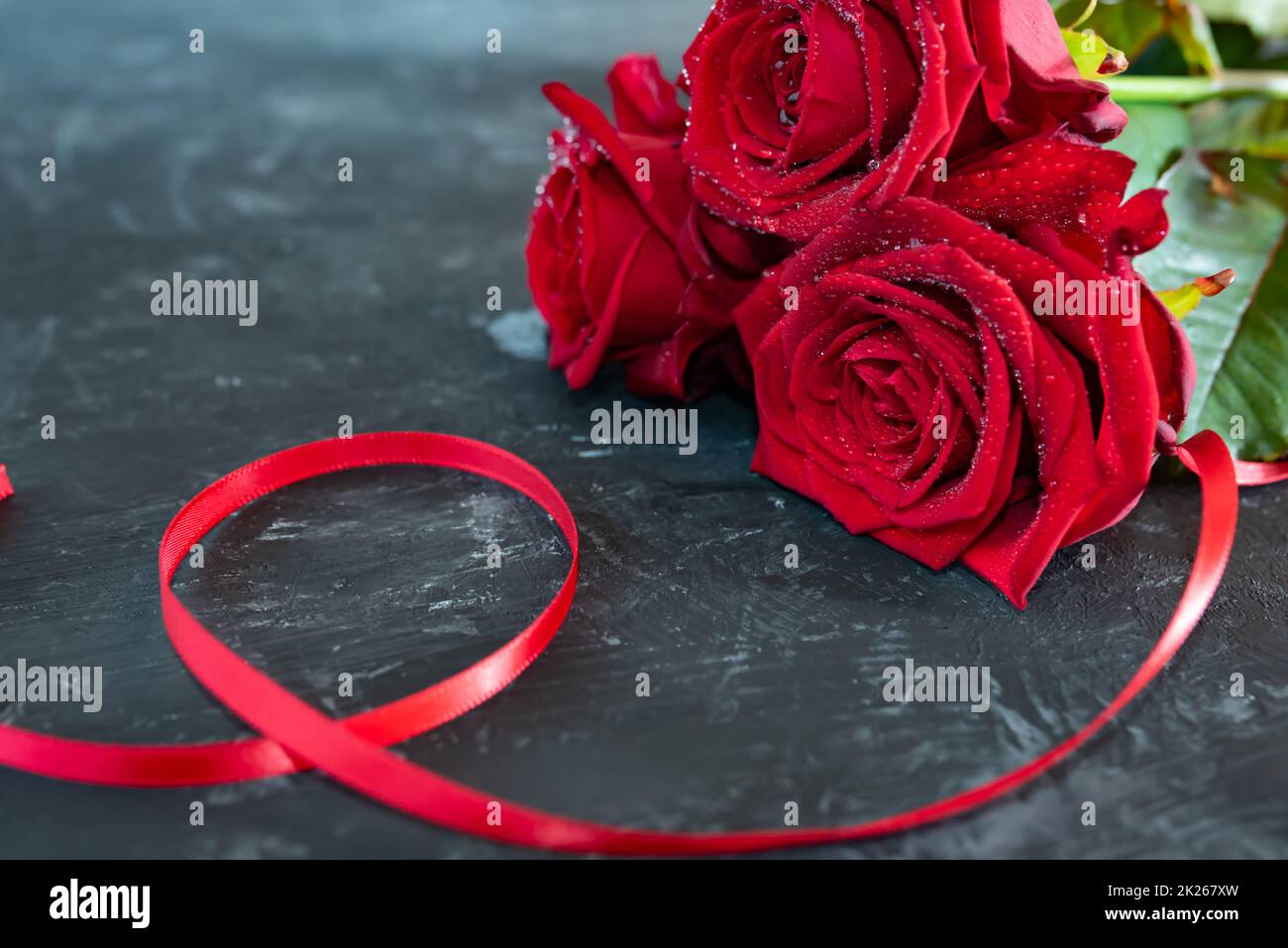 Rote Rosen mit Band auf grauer Steinplatte Stockfoto