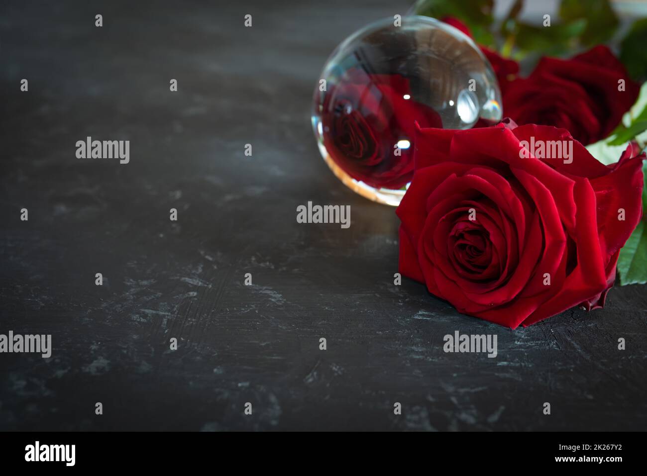 Rote Rosen spiegeln sich in einer Glaskugel wider Stockfoto