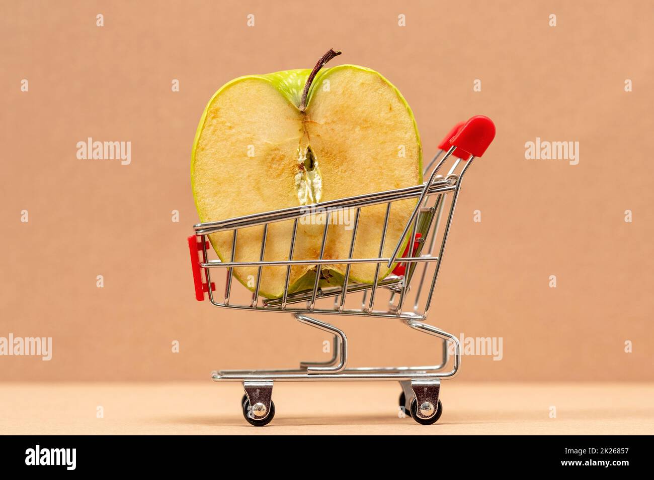 Die Hälfte des Apfels in einem kleinen Supermarkt-Einkaufswagen Stockfoto
