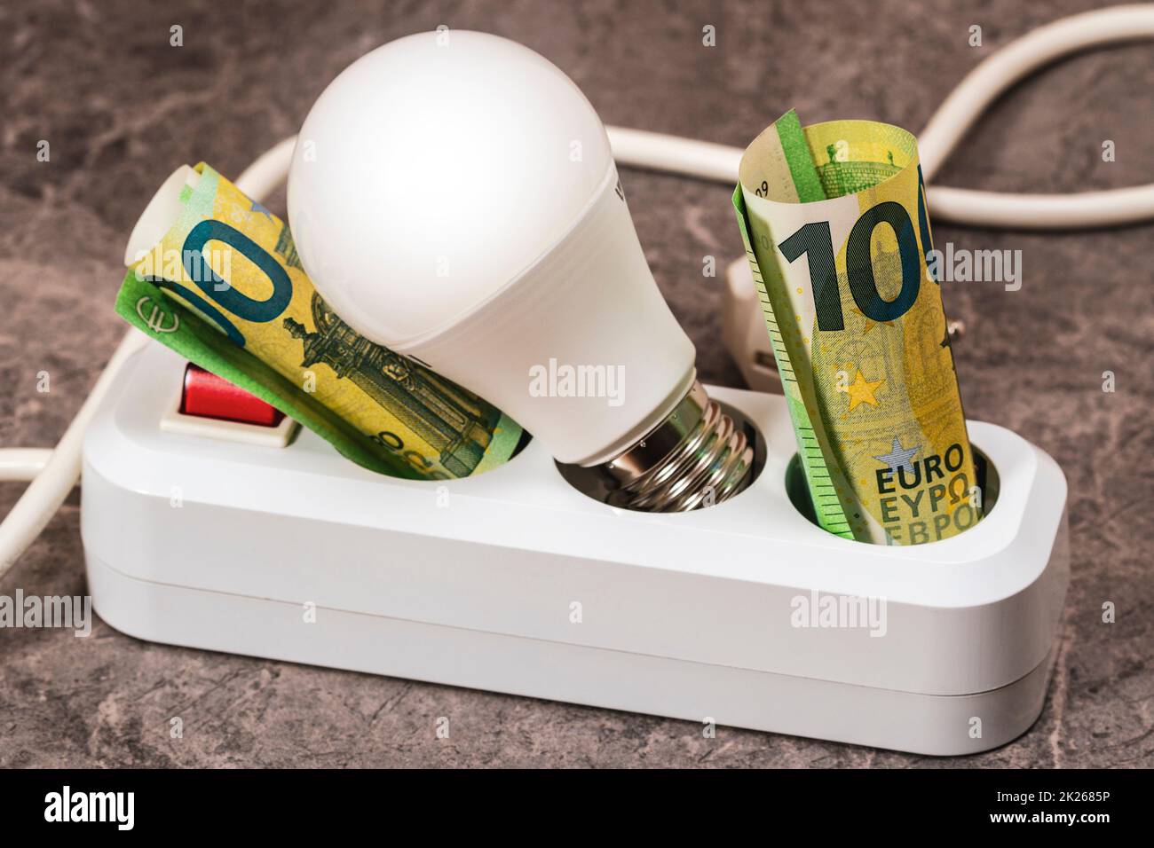 Euro Money und LED-Glühlampe in eine Steckdosenleiste eingesetzt Stockfoto