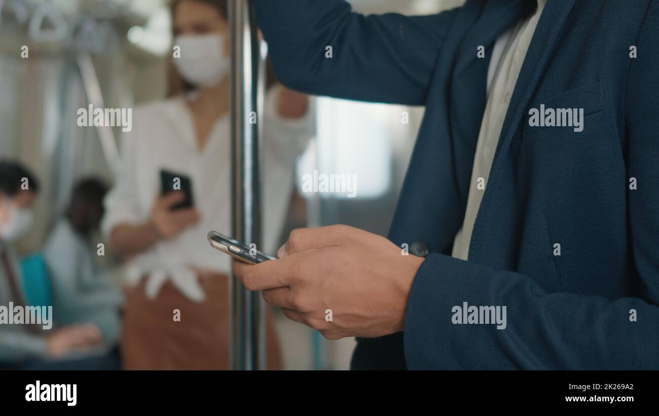 Ein Geschäftsmann, der auf dem Sitz steht und ein modernes Smartphone benutzt, um im Internet Nachrichten im Elektrozug zu lesen Stockfoto
