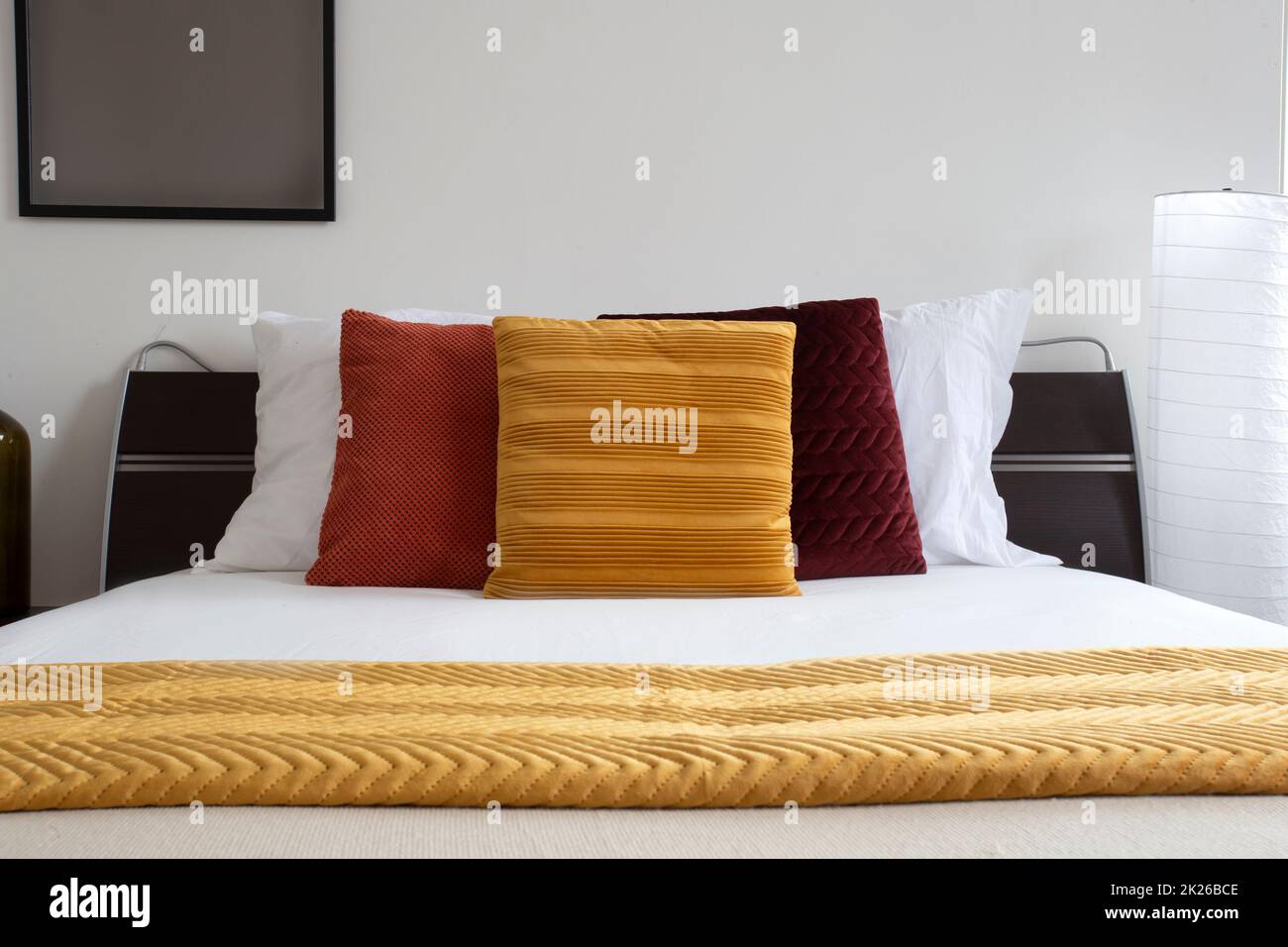 Das Bett war gemacht. Modernes und ordentliches Bett in der Nacht. Elegantes Doppelbett. Nahaufnahme eines Schlafzimmers in einem Hotelzimmer. Bett mit weißen Laken und Kissen. Stockfoto