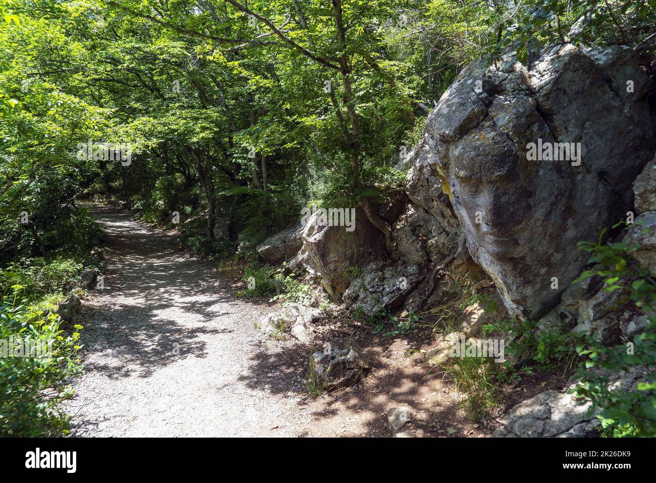 Ein Gesicht, das in einen großen Stein gemeißelt wurde, entlang eines sonnigen Weges. Krim. Jalta. Stockfoto