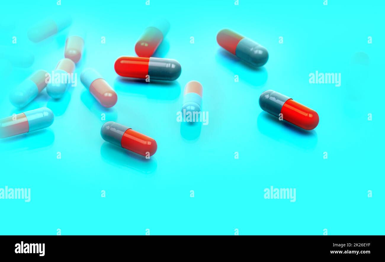Selektiver Fokus auf grau-orangefarbene Antibiotikakapseln auf blauem Hintergrund. Pharmazeutische Industrie. Toxikologie und pharmakologisches Konzept. Antibiotikaresistenz. Herstellung von Kapselpillen. Stockfoto