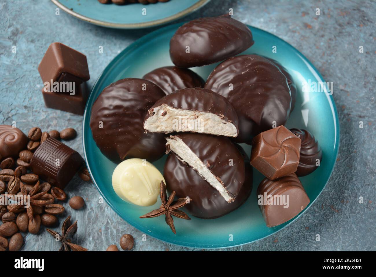 Zefir (zephyr), Kaffeetasse, Bohnen, Schokolade auf Küchentisch, Auswahl an dunklen, weißen und milchigen Schokoladenbonbons. Stockfoto
