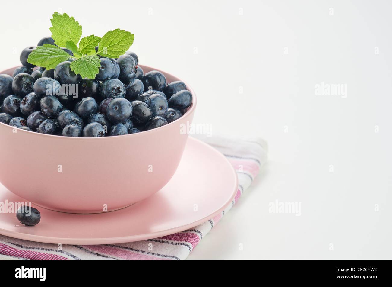 Reife Heidelbeere in einer rosa Keramikplatte auf einem weißen Tisch, schmackhafte und nützliche Beere Stockfoto