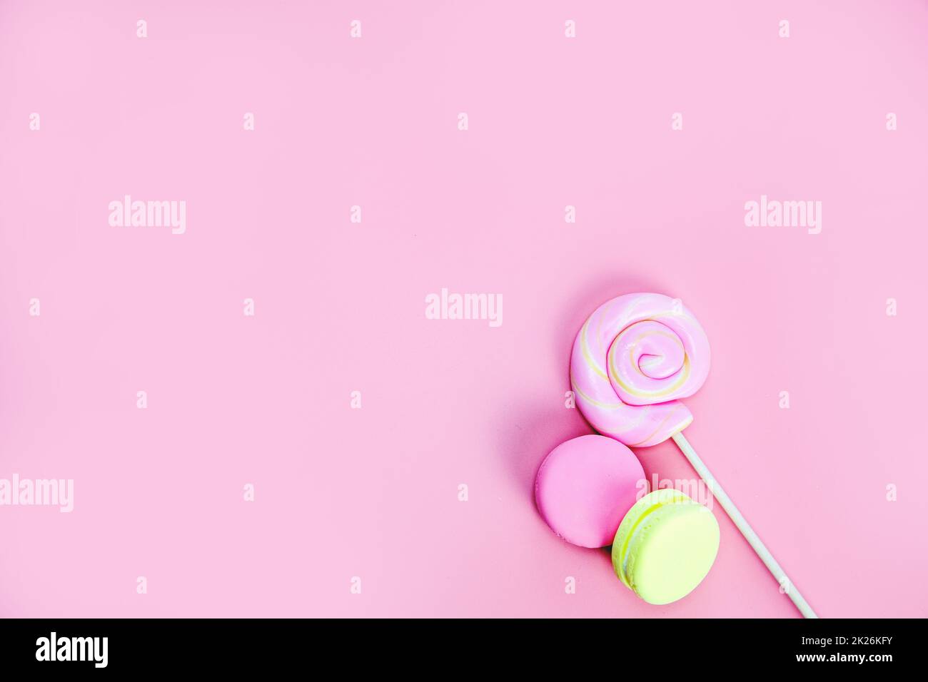 Candy Sweets Konzept. Rosa Lollypop und Donuts, Macarons auf rosa Hintergrund, Copy Space Draufsicht Stockfoto