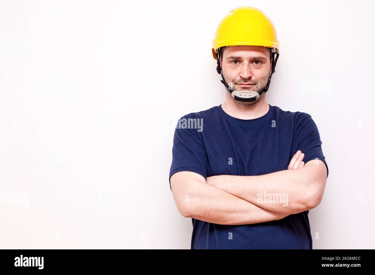 Bauarbeiter hinter weißem Hintergrund. Trägt eine grüne Maske und einen gelben Helm Stockfoto