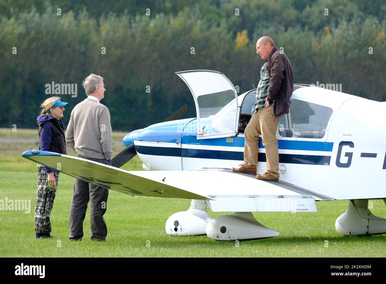 General Aviation Pilot und Kollegen unterhalten sich neben einem leichten Flugzeug auf einem Grasflugplatz in Großbritannien September 2022 Stockfoto