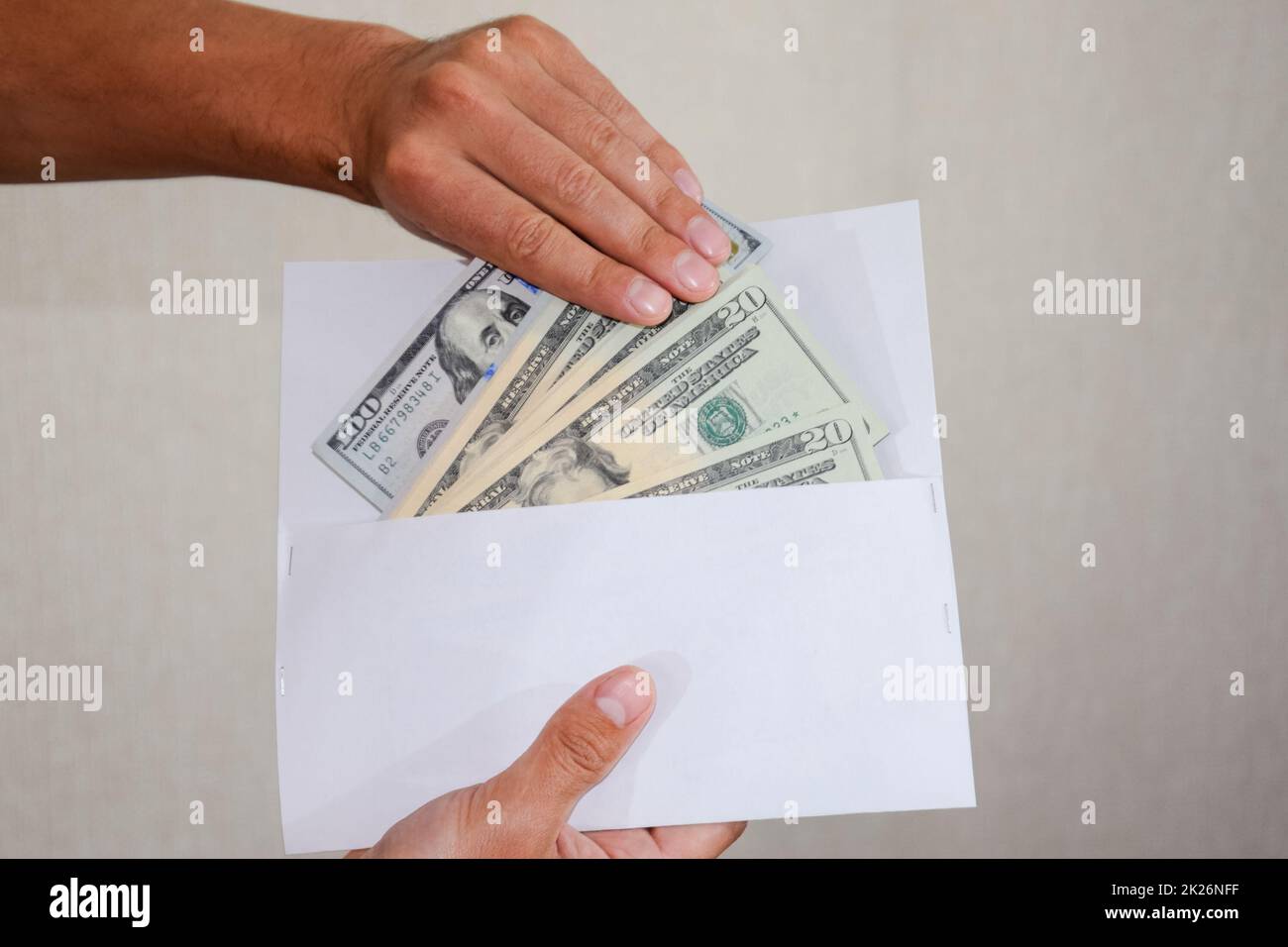 Geld in weißem Umschlag in den Händen eines Mannes. Dollar, ein Bündel Dollar. Stockfoto