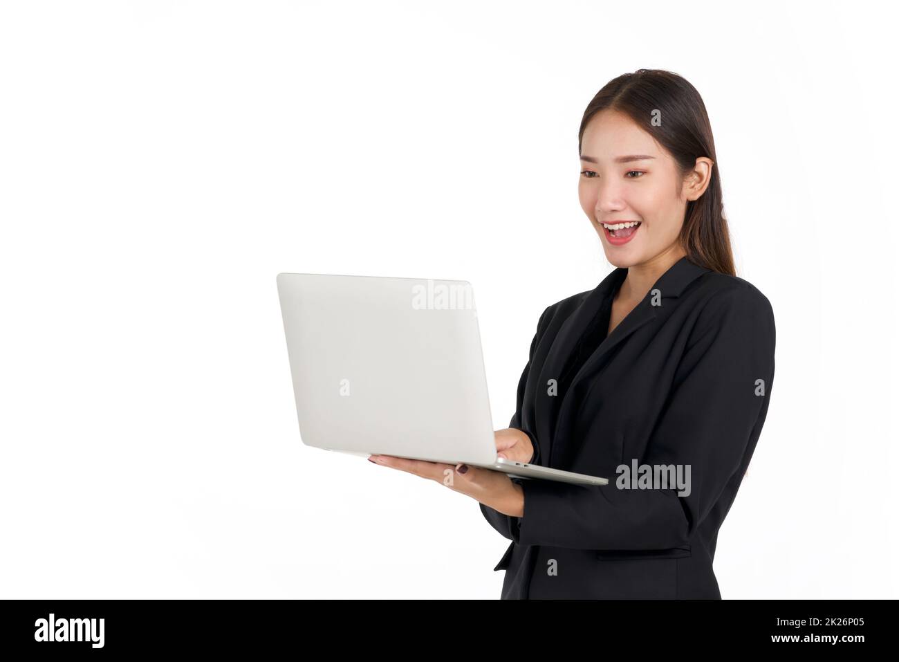 Junge asiatische Geschäftsfrau in einem schwarzen Anzug, die in der Hand auf den Laptop-Computermonitor schaut. Porträt auf weißem Hintergrund mit Studiolicht. Stockfoto