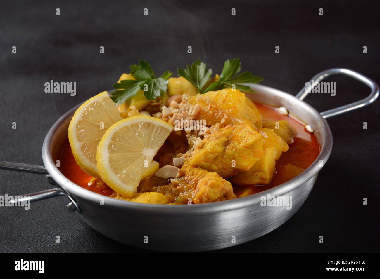 Ein Chicken Massaman Curry in schwarzer Schüssel auf dunklem Hintergrund. Massaman Curry ist das beste thailändische Gericht mit Hühnerfleisch, Kartoffeln, Zwiebeln und vielen Gewürzen, das von malaiischen und thailändischen muslimischen Kulturen beeinflusst wird. Stockfoto
