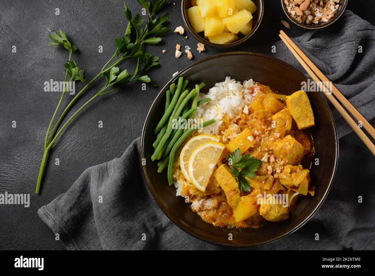 Ein Chicken Massaman Curry in schwarzer Schüssel auf dunklem Hintergrund. Massaman Curry ist das beste thailändische Gericht mit Hühnerfleisch, Kartoffeln, Zwiebeln und vielen Gewürzen, das von malaiischen und thailändischen muslimischen Kulturen beeinflusst wird. Stockfoto