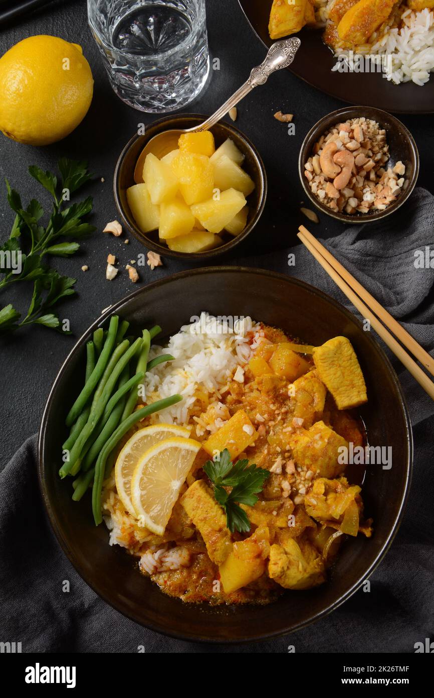 Ein Chicken Massaman Curry in schwarzer Schüssel auf dunklem Hintergrund. Massaman Curry ist das beste thailändische Gericht mit Hühnerfleisch, Kartoffeln, Zwiebeln und vielen Gewürzen, das von malaiischen und thailändischen muslimischen Kulturen beeinflusst wird. Stockfoto