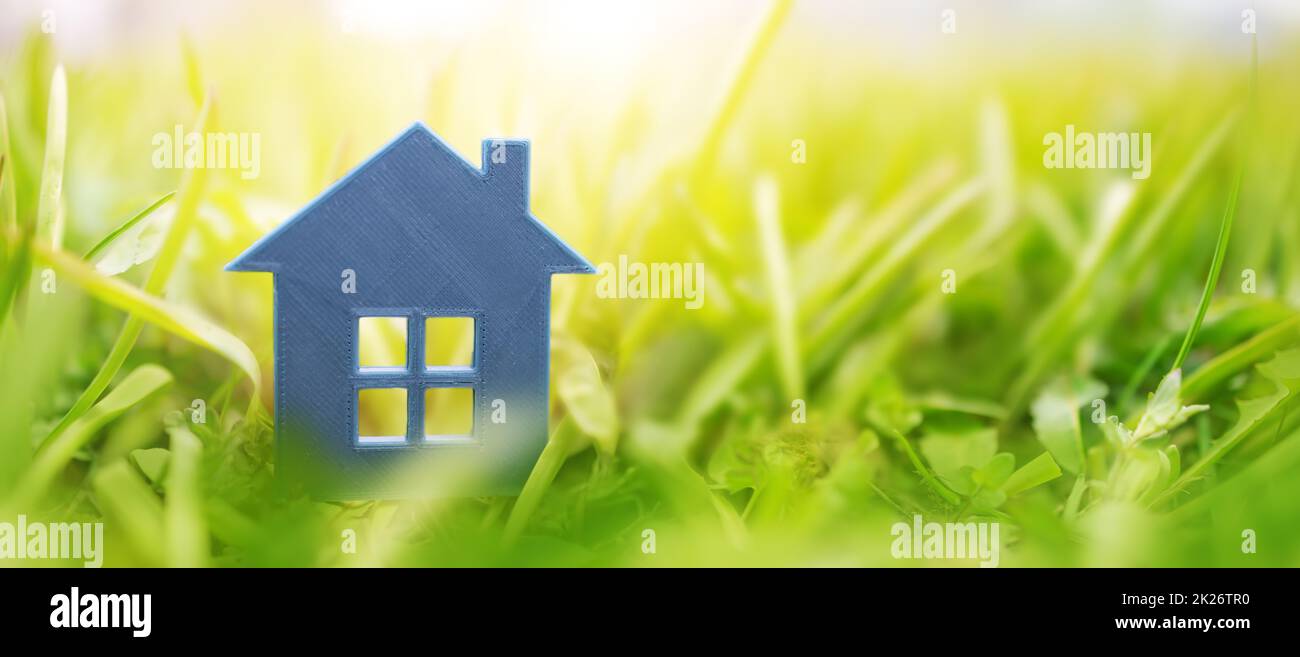 Graues Plastikmodell des Hauses auf dem frischen Gras an einem sonnigen Tag. Stockfoto