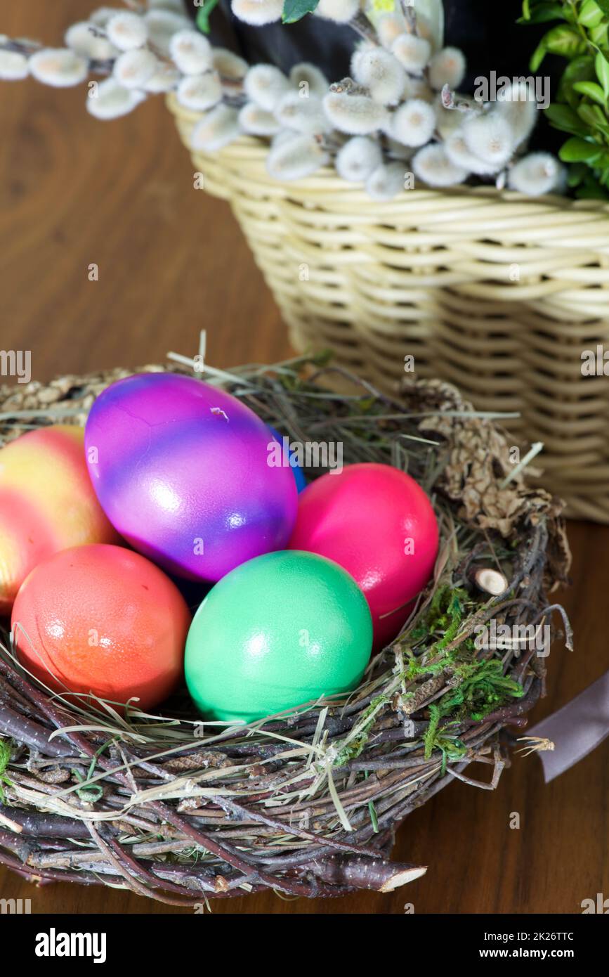 Ostermotive mit Strohhasen, bunten Eiern, Nest und Blumen Stockfoto
