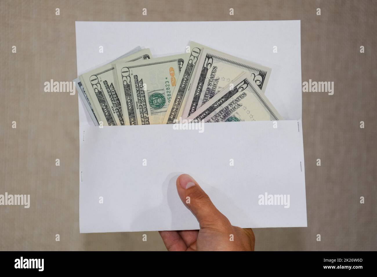 Geld in weißem Umschlag in den Händen eines Mannes. Dollar, ein Bündel Dollar. Stockfoto