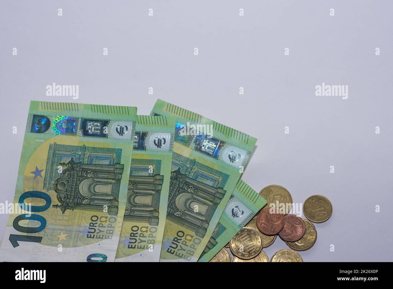 Viele 100-Euro-Scheine und -Münzen auf grauem Hintergrund Stockfoto