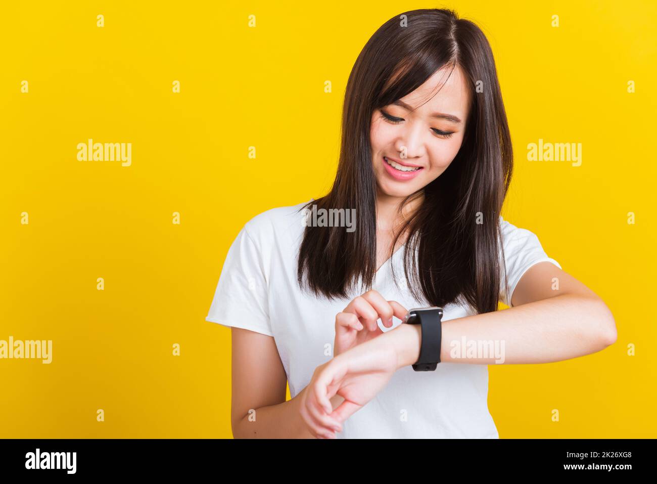 Junge Frau, die lächelt und mit dem Finger auf ihre intelligente Armbanduhr zeigt Stockfoto
