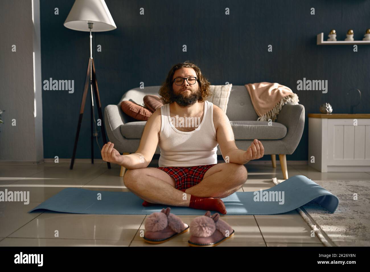 Lustiger fetter Mann meditiert zu Hause Yoga üben Stockfoto