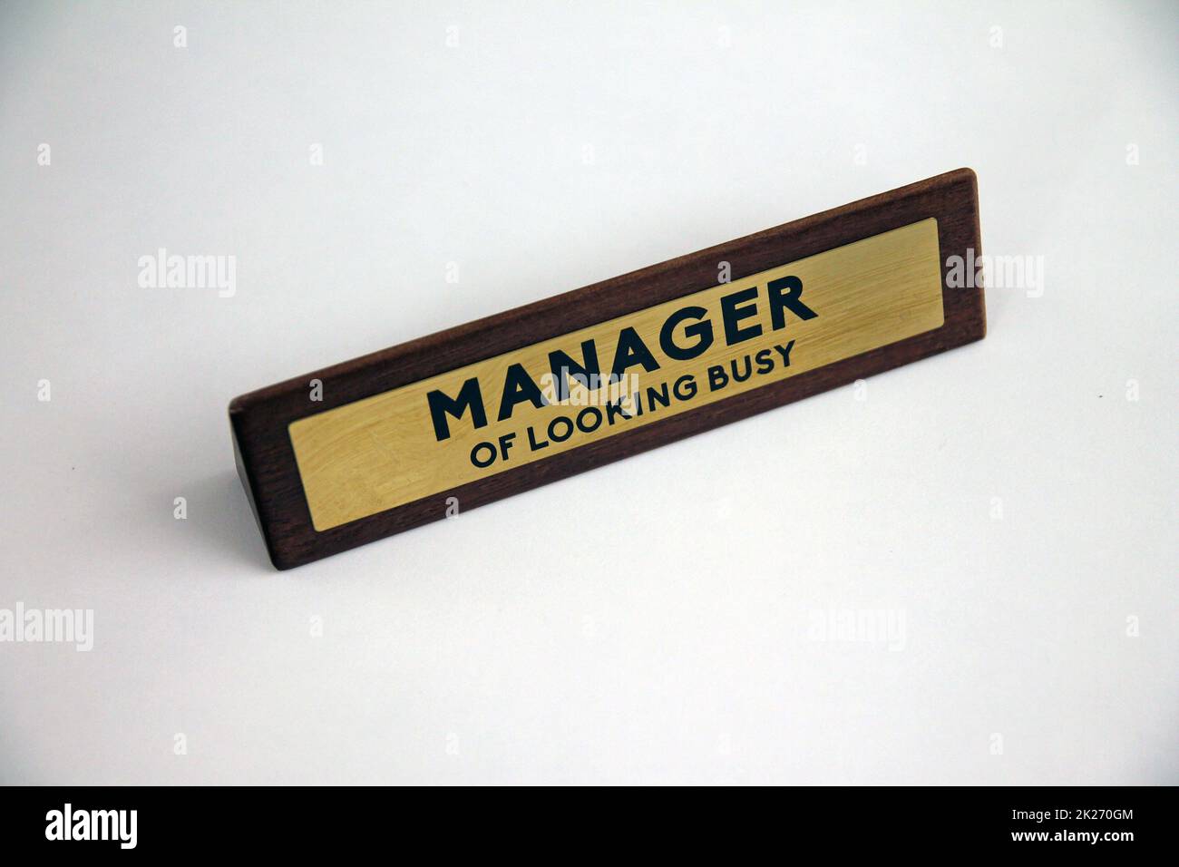 Der Manager sieht aus wie ein vielbeschäftigtes Holz- und Metallschild auf einem weißen Regal Stockfoto