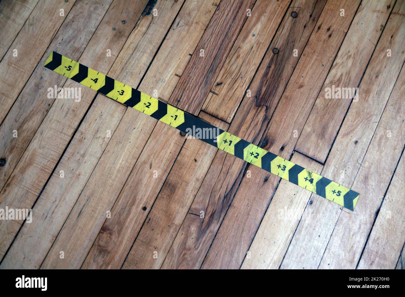 Der schwarze und gelbe Messpfeil klebt auf dem Holzboden Stockfoto