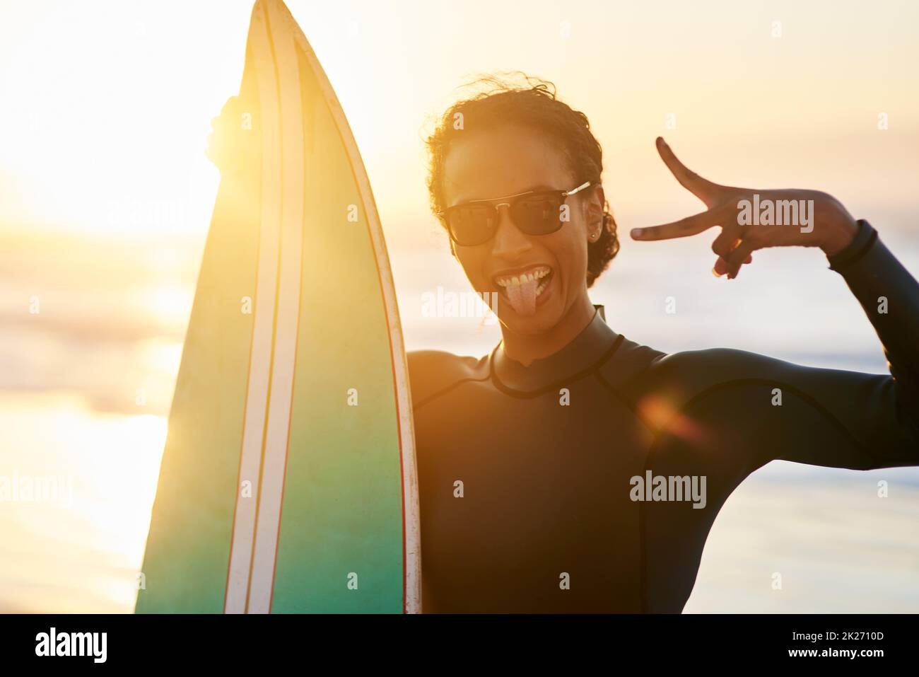 Kommen Sie und surfen Sie. Porträt einer schönen jungen Surferin, die mit ihrem Surfbrett am Strand posiert. Stockfoto