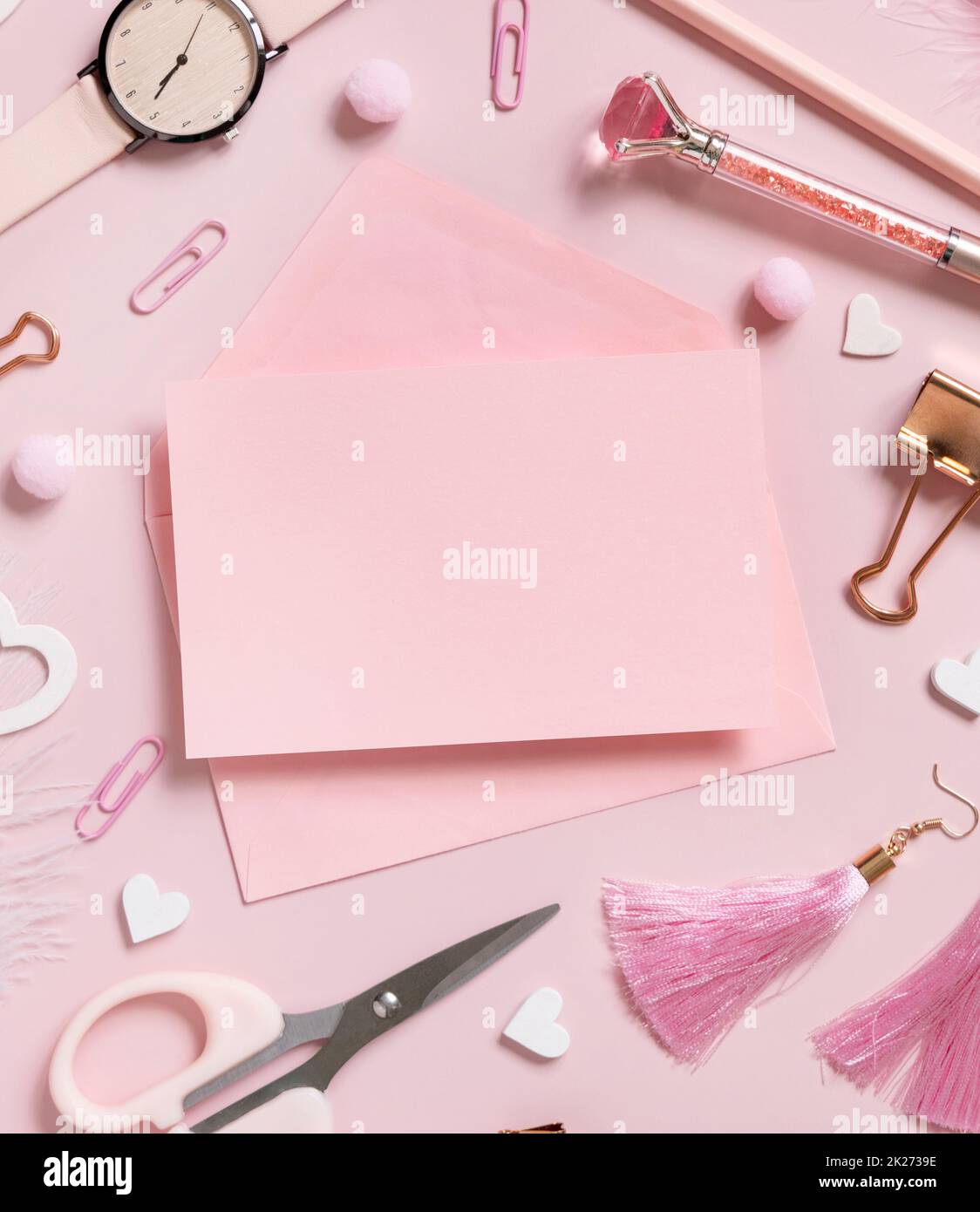 Pinke Papierkarte mit Umschlag, Accessoires für Schulmädchen und Herzen auf pastellrosa Draufsicht, Modell Stockfoto
