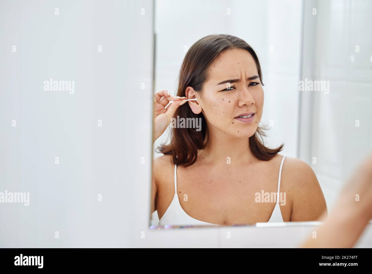 Das ist so unangenehm. Aufnahme einer jungen Frau, die ihre Ohren während ihrer morgendlichen Routine zu Hause mit einem Wattestäbchen putzt. Stockfoto