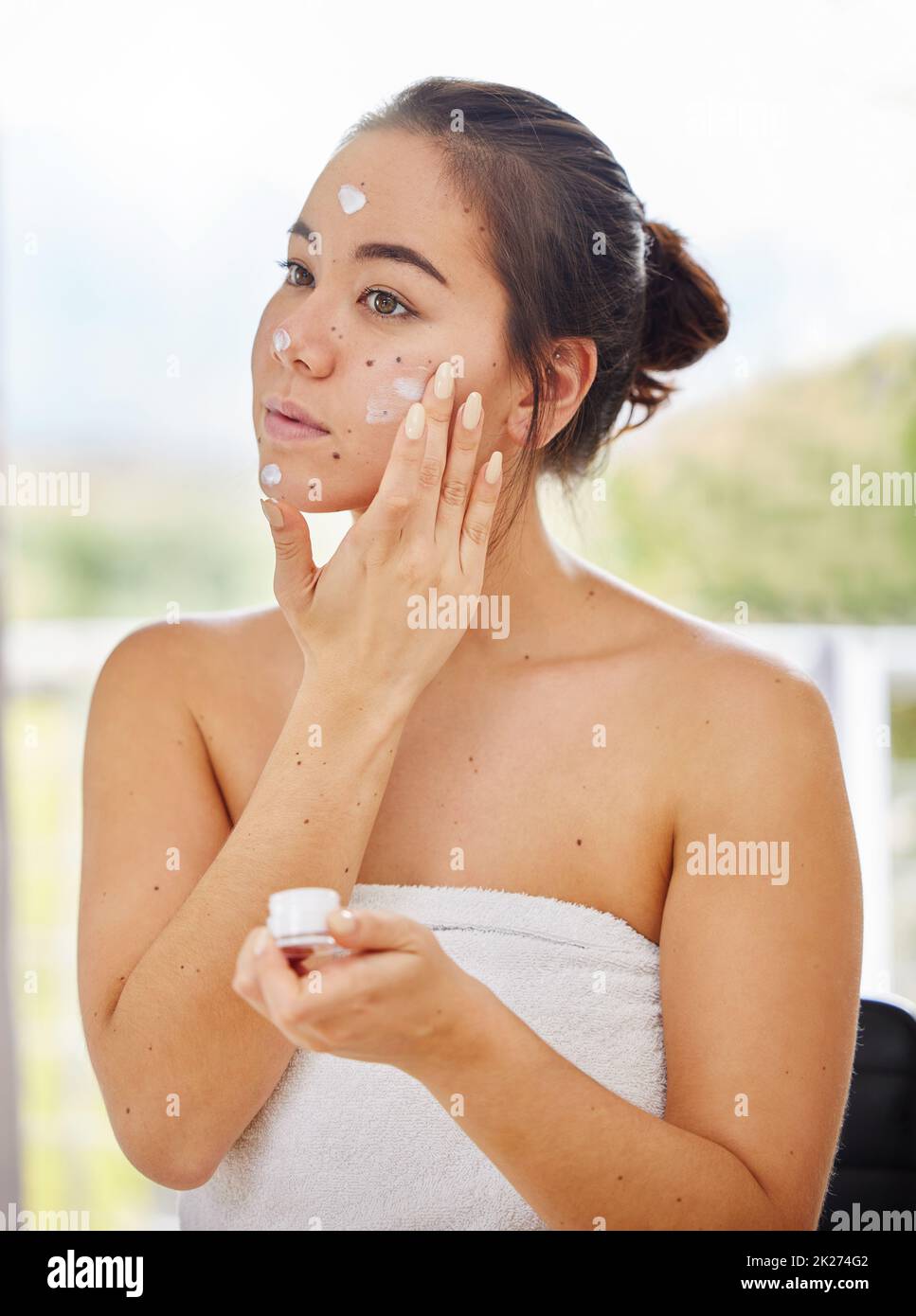 Ich habe den ganzen Tag über Feuchtigkeit im Gesicht. Aufnahme einer jungen Frau, die während ihrer morgendlichen Schönheitsroutine Feuchtigkeitscreme auf ihr Gesicht anwendet. Stockfoto